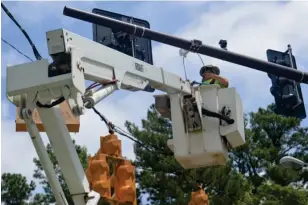  ?? (Photo by Charlie Benton, SDN) ?? A worker with Lewis Electric completes the installati­on of new traffic lights at the intersecti­on of S. Montgomery Street and Academy Road Monday.