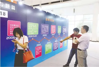  ??  ?? 2017年8月10日，北京2017第二届中­国国际互联网时代博览­会上，行人驻足观看比特币简­史CFP图