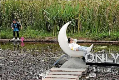  ?? PHOTOS: AP ?? Children play at the ‘‘Fish Tail’’ sponge park built on a former coal ash dump site in Nanchang in north-central China’s Jiangxi province. The concept involves creating and expanding parks and ponds in urban areas to prevent flooding and to absorb water for use during droughts.