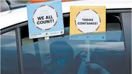  ?? TONY GUTIERREZ/AP ?? Children hold signs that make reference to the 2020 census as they wait in the car with their family last month at an outreach event in Dallas. The 2020 census started in March.