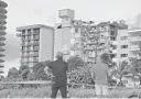  ?? FILE ?? People look at the rubble at Champlain Towers South Condo in Surfside, located at 8777 Collins Avenue, a part of which collapsed in the early morning in Surfside on June 24.