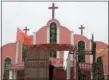  ?? NG HAN GUAN — THE ASSOCIATED PRESS ?? A worker looks out from a truck parked in front of a church and the Chinese national flag near the city of Pingdingsh­an in central China’s Henan province.