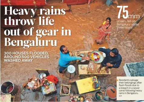  ?? AFP ?? Residents salvage their belongings after flash floods due to a breach in a sewer canal following heavy rains in Bengaluru.