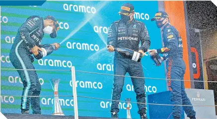  ?? / FOTO: AFP ?? Lewis Hamilton (izq.) festeja en el podio, junto a su coequipero Valtteri Bottas y Max Verstappen.