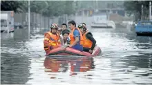  ?? CHINATOPIX ?? Rescuers use a raft to transport people along a flooded street in Shenyang in northeaste­rn China’s Liaoning Province. Dozens of people have been killed and dozens more are missing across China after a round of torrential rains swept through the country...