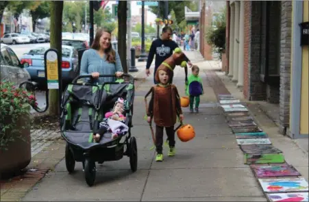  ?? MICHILEA PATTERSON — FOR DIGITAL FIRST MEDIA ?? A family walks along downtown High Street in Pottstown during Haunts on High. The annual event encourages children to dress in costume then trick or treat at vendor tables and area businesses.