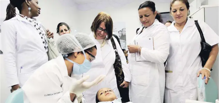  ??  ?? ► Médicos cubanos observan un procedimie­nto dental durante una sesión de entrenamie­nto en una clínica de salud en Brasilia, en 2013.