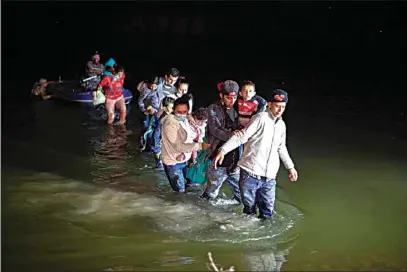  ?? DARIO LOPEZ-MILLS / AP ?? Migrant families, mostly from Central American countries, wade through shallow waters after being delivered by smugglers on small inflatable rafts on U.S. soil in Roma, Texas, Wednesday.