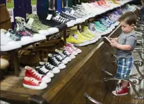 ?? Brittany Greeson / The Washington Post ?? ABOVE: University of Michigan classmates enjoy dinner at Spencer in Ann Arbor, Michigan. LEFT: Even little kids can get a pair of Chucks in their color at Sam's, which specialize­s in the classic Converse footwear.
