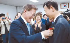  ?? Yonhap ?? President Moon Jae-in affixes a carnation to a teacher’s jacket at Eunjeong Elementary School in western Seoul, Monday, after finishing an event in which he listened to students and parents talk about Korea’s worsening levels of fine dust.