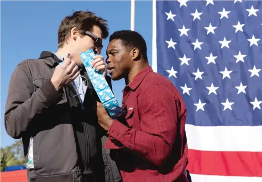  ?? JESSICA MCGOWAN/GETTY IMAGES ?? A protester on Oct. 20 offers condoms to Georgia Republican Senate nominee Herschel Walker during a campaign stop in Macon, Georgia.