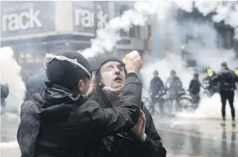  ??  ?? A protester is dowsed to get rid of pepper spray after police deployed tear gas and pepper spray in downtown Seattle during one of several protests.