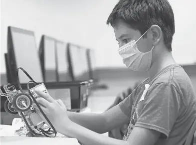  ??  ?? Amid concerns of the spread of COVID- 19, sixth grader Salih Tas wears a mask as he works on building a robot during a summer camp Tuesday at Wylie High School in Wylie, Texas. LM OTERO/ AP