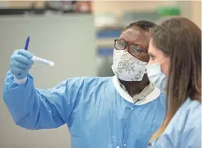  ?? MAX GERSH / THE COMMERCIAL APPEAL ?? Dr. Toh Gang (left) and medical laboratory technician Amanda Mcmillan look at a COVID-19 test sample Thursday, July 23, 2020, at Poplar Healthcare in Memphis.