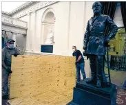  ?? AP ?? Workmen place plywood beside the statue of Robert E. Lee in the Old House Chamber inside the Virginia State Capitol in Richmond on Thursday. All busts and plaques relating to the Confederac­y were removed.