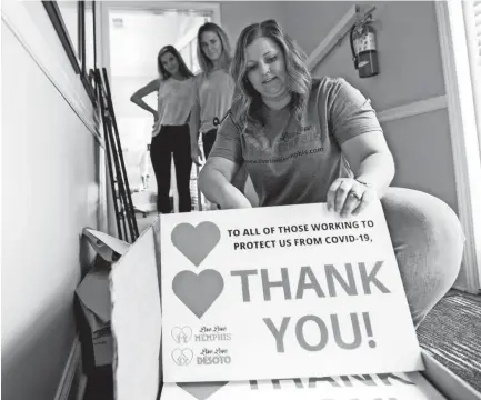  ?? MAX GERSH / THE COMMERCIAL APPEAL ?? Aubree Vaccaro (from left) and Averi Davis watch as April Darnell, director of operations for Live Love Memphis and Live Love Desoto, opens a new box of signs Tuesday, April 28, 2020, in Germantown.