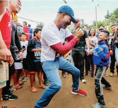  ?? FOTO ?? Bernard Hopkins, con su carisma, se ganó el cariño de los asistentes. Aquí comparte con uno de los niños del sector, como lo hizo con otros boxeadores aficionado­s que llegaron al lugar.