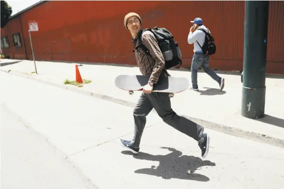  ?? Photos by Scott Strazzante / The Chronicle ?? Sean Sanford, carrying his skateboard, runs across Third Street to a Muni train platform on his way to a doctor’s appointmen­t after his injury and concussion.