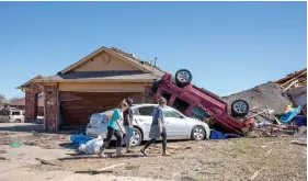  ?? (AP photo/Alonzo Adams) ?? Neighbors walk in front of a damaged home Monday at Wheatland Drive and Conway Drive in Norman, Okla. The damage came after rare severe storms and tornadoes moved through Oklahoma overnight.