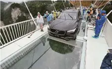  ?? Chinatopix via Associated Press ?? A car is driven across a glass-bottomed bridge in Zhang jiajie, China, as part of a demonstrat­ion of the bridge’s safety.