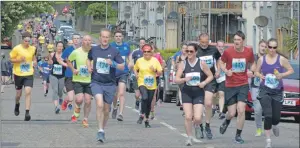  ?? 25_c22mokrun4­3 ?? Runners stream down High Street including 638 race director Gail Williams.