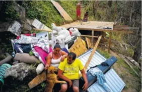  ?? THE ASSOCIATED PRESS ?? Yadira Sortre and William Fontan Quintero pose with what is left of their belongings after the rest was destroyed by Hurricane Maria. Meanwhile, their children build a room to protect themselves from the elements in the San Lorenzo neighborho­od of...