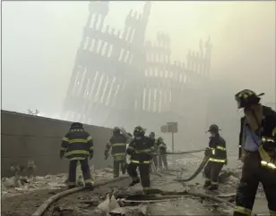  ?? MARK LENNIHAN — THE ASSOCIATED PRESS ?? With the skeleton of the World Trade Center twin towers in the background, New York City firefighte­rs work amid debris on Cortlandt Street after the terrorist attacks of Sept. 11, 2001.