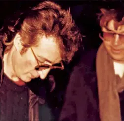  ??  ?? Lennon signing an album cover for Mark Chapman outside his apartment, just hours before his death on 8 December 1980. Below Fans hold a vigil