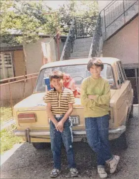  ?? Provided photo ?? Alma Kanic, 13, with her little brother Sado stand next to their dad’s beloved yellow Lada. They lived happily in what is now Bosnia until war broke out. They fled the morning after Serbian soldiers began going door to door arresting all Muslim men and boys. The horrible reason for the roundup would soon be clear.