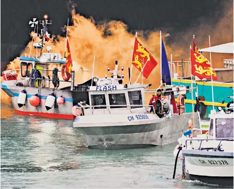  ??  ?? French fishermen, angry over the loss of access to waters off their coast, set off smoke flares and wave the flag of Normandy near the main port of St Helier in Jersey