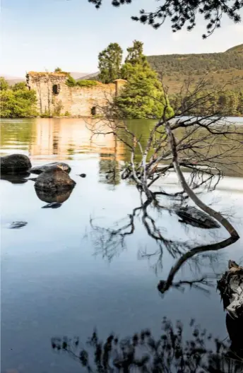  ??  ?? Lit by the June sun, the crumbling island castle casts a golden reflection on the loch. Rising water has covered a causeway which once linked it to the shore.