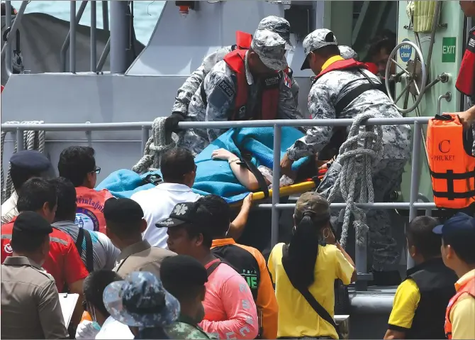  ??  ?? Thai rescuers move a passenger on a stretcher at Chalong pier in Phuket on Friday. At least 33 Chinese passengers were killed and 23 others still missing after two boats carrying 133 tourists capsized in rough sea waters in southern Thailand on...