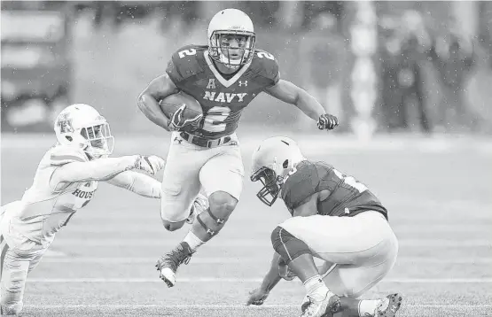  ?? Mitchell Layton photos / Getty Images ?? Navy’s Toneo Gulley, center, slips past a UH defender on this run during the first quarter of Saturday’s game. Navy finished with 306 rushing yards.