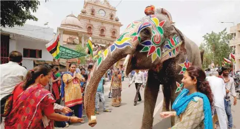  ?? — Reuters ?? Devotees give money to a decorated elephant outside the Jagannath temple on the eve of the annual Rath Yatra, or chariot procession, in Ahmedabad, on Saturday.