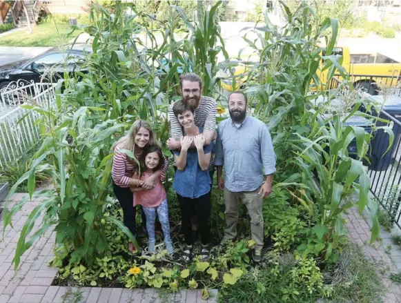  ?? STEVE RUSSELL/TORONTO STAR ?? Anthony McCanny and his partner Sarah Kern, centre, are flanked by, from left, Dara Solomon, Stella Rosenthal and Jay Rosenthal, in Solomon and Rosenthal’s front-yard “farm.”