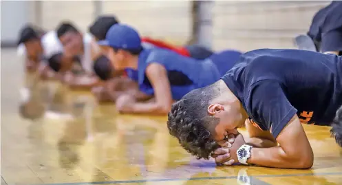  ?? PHOTOS BY GABRIELA CAMPOS/THE NEW MEXICAN ?? Joby Atenio holds the final moments of a plank position during football workouts in the McCurdy Charter School gymnasium on Thursday. The Bobcats were forced to take practice inside due to rain.