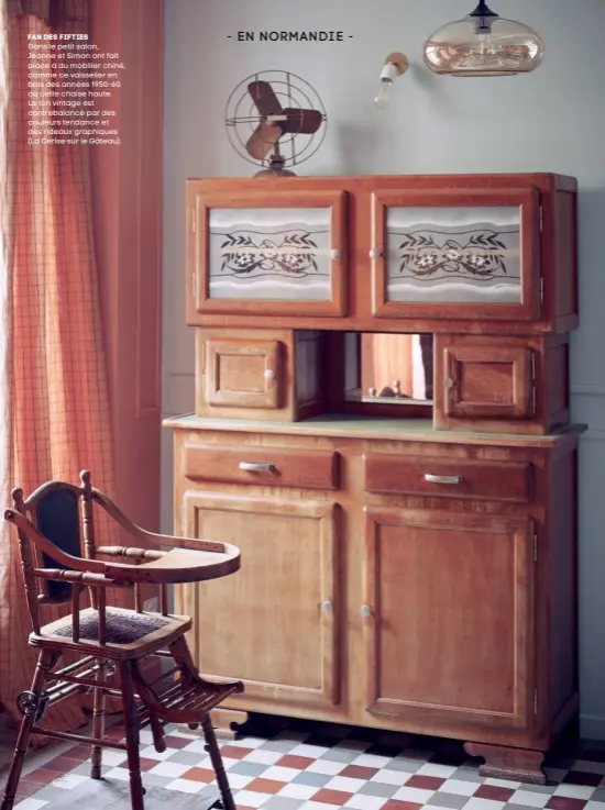  ??  ?? fan des fifties Dans le petit salon, Jeanne et Simon ont fait place à du mobilier chiné, comme ce vaisselier en bois des années 1950-60 ou cette chaise haute. Le ton vintage est contrebala­ncé par des couleurs tendance et des rideaux graphiques (La Cerise sur le Gâteau).