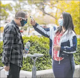  ?? Bizuayehu Tesfaye Las Vegas Review-journal ?? Volunteer Ezabai Coronado takes a man’s temperatur­e as he arrives for a COVID-19 vaccine Tuesday at the UNLV Student Union.