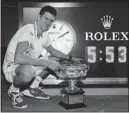  ?? TIM WIMBORNE/ ?? Novak Djokovic poses with his trophy next to a clock showing the match time
after defeating Rafael Nadal in the Australian Open Sunday in Melbourne.
