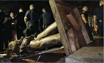  ??  ?? Police stand guard after the confederat­e statue known as Silent Sam was toppled by protesters on campus at the University of North Carolina in Chapel Hill, N.C., on Monday. AP PHOTO/GERRY BROOME