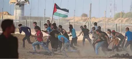  ?? [FOTO REUTERS] ?? Warga Palestin terpaksa berlari menyelamat­kan diri selepas tentera Zionis mengejar dan melepaskan tembakan termasuk gas pemedih mata ke arah mereka ketika satu bantahan di sempadan Gaza-israel, kelmarin.
