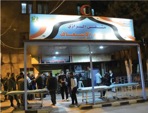  ?? (Reuters) ?? PEOPLE STAND in front of a hospital after what the Syrian state media said was a suspected toxic gas attack in Aleppo last week.