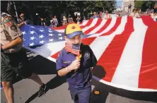  ?? Michael Macor / The Chronicle ?? Eight-year-old Morgan Jekat, a member of Cub Scouts Pack 991, helps carry a huge U.S. flag at Redwood City’s parade.