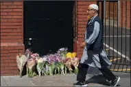  ?? JOEL GOODMAN/LONDON NEWS PICTURES ?? A man walks past flowers left in memory of the dead and injured Monday outside Finsbury Park Mosque in London. A hired van was driven into people on Whadcoat Street in Finsbury Park in North London after late night prayers at a nearby mosque.