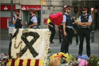  ?? AP PHOTO/EMILIO MORENATTI ?? Police officers stand guard next to flags, flowers, messages and candles to the victims on Barcelona’s historic Las Ramblas promenade on the Joan Miro mosaic, embedded in the pavement where the van stopped after killing at least 14 people in Barcelona,...