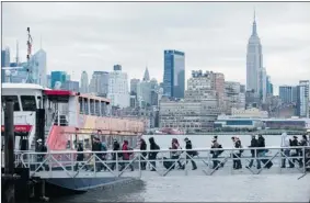  ??  ?? People board the ferry, one of the few transporta­tion systems functionin­g in Sandy’s wake, in Hoboken, N.J. Kennedy and Newark Liberty airports reopened with limited service.