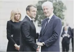  ??  ?? 0 Emmanuel Macron, watched by wife Brigitte, greets Bill Clinton