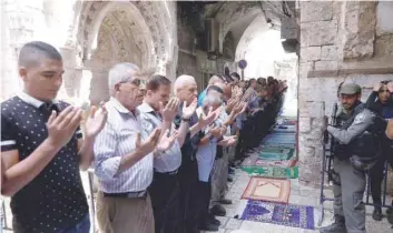  ?? Reuters ?? Palestinia­n men pray as Israeli security forces secure outside the compound known to Muslims as Noble Sanctuary and to Jews as Temple Mount, in Jerusalem’s Old City on Wednesday. —