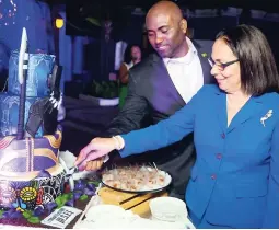  ??  ?? Minister of Science, Energy and Technology Dr Andrew Wheatley cuts the cake with Minister of Labour and Social Security Shahine Robinson.