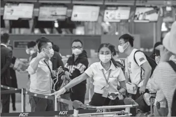  ?? GEMUNU AMARASINGH­E/AP PHOTO ?? An airline staffer assists tourists from Wuhan, China, as they wait for a charter flight back to Wuhan at the airport in Bangkok, Thailand. A group of Chinese tourists who have been trapped in Thailand since Wuhan was locked down due to an outbreak of a new virus returned to China on Friday.